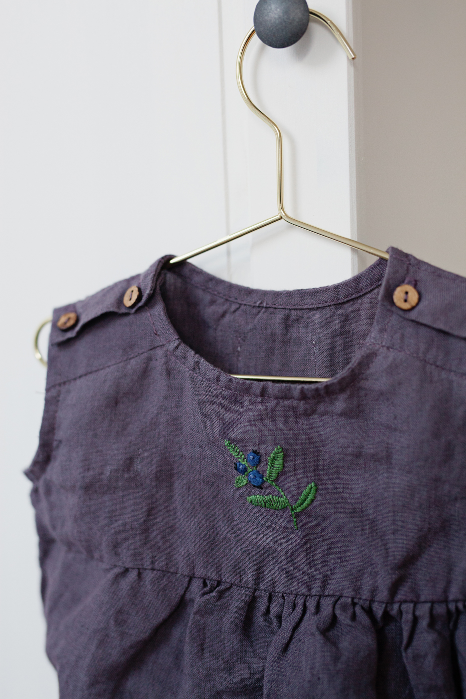 Purple linen romper with hand-embroidered blueberry by La Petite Alice. 